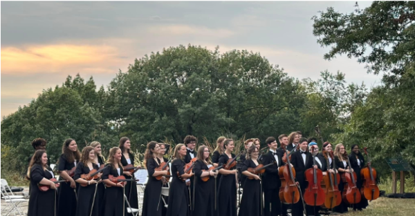 The orchestra stands ready to begin their performance. 