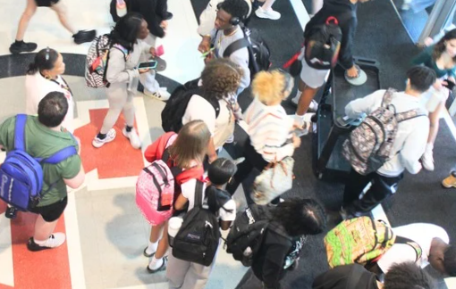 Mary Anderson, a member of the safety team, watches as students line up to unlock their Yondr pouches after dismissal.
